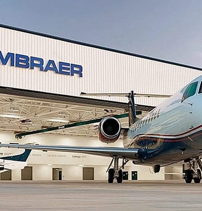 Imagem mostra avião e logo da Embraer (EMBR3)