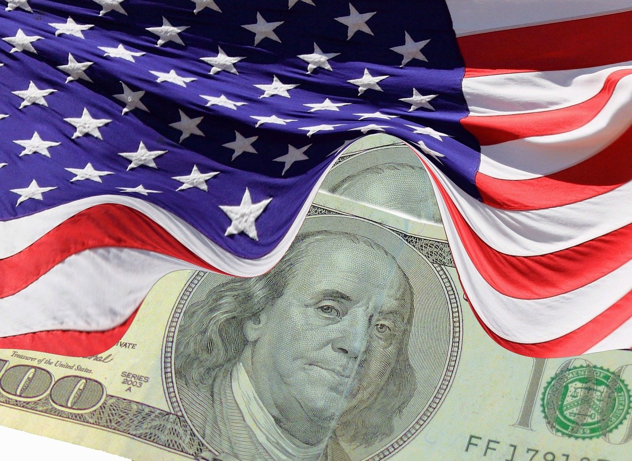 Imagem com bandeira americana e dólar faz alusão a indicadores econômicos dos EUA