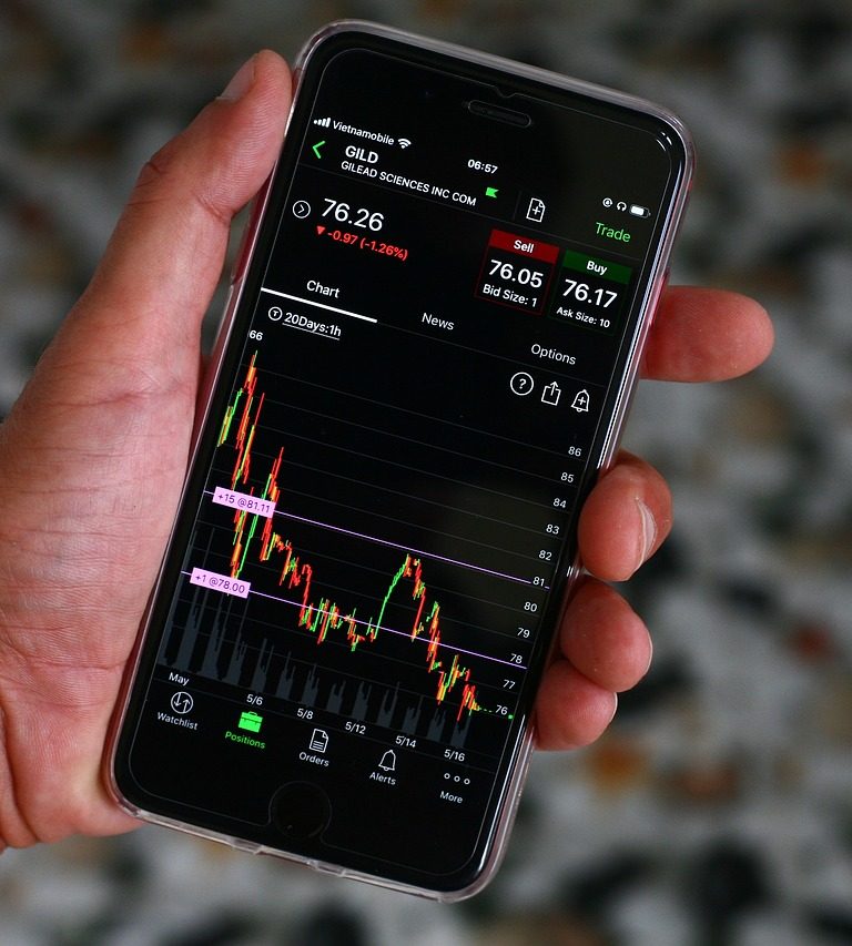 Imagem mostra investidor acompanhando no celular os tipos de derivativos na bolsa