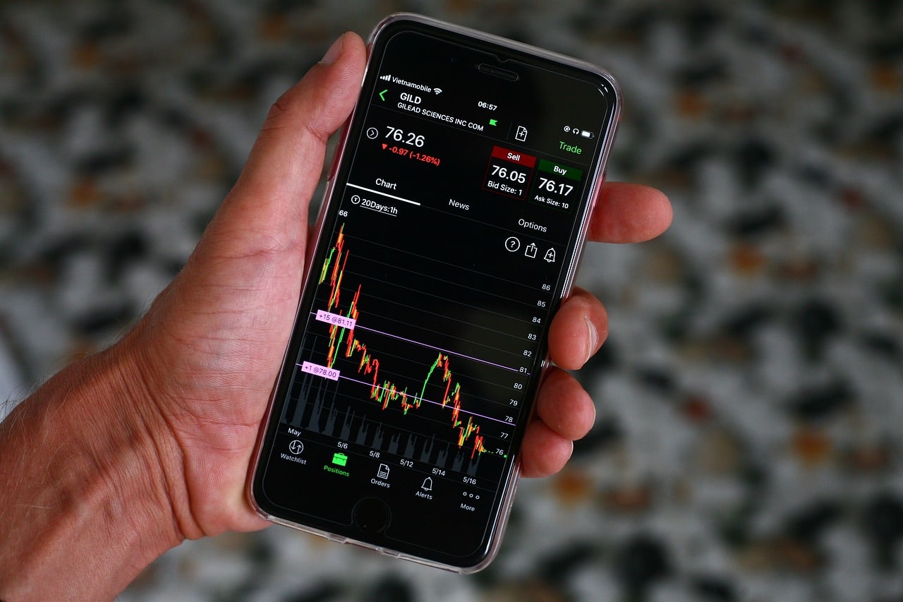 Imagem mostra investidor acompanhando no celular os tipos de derivativos na bolsa