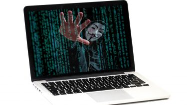 Imagem mostra hacker invadindo computador representando golpes financeiros